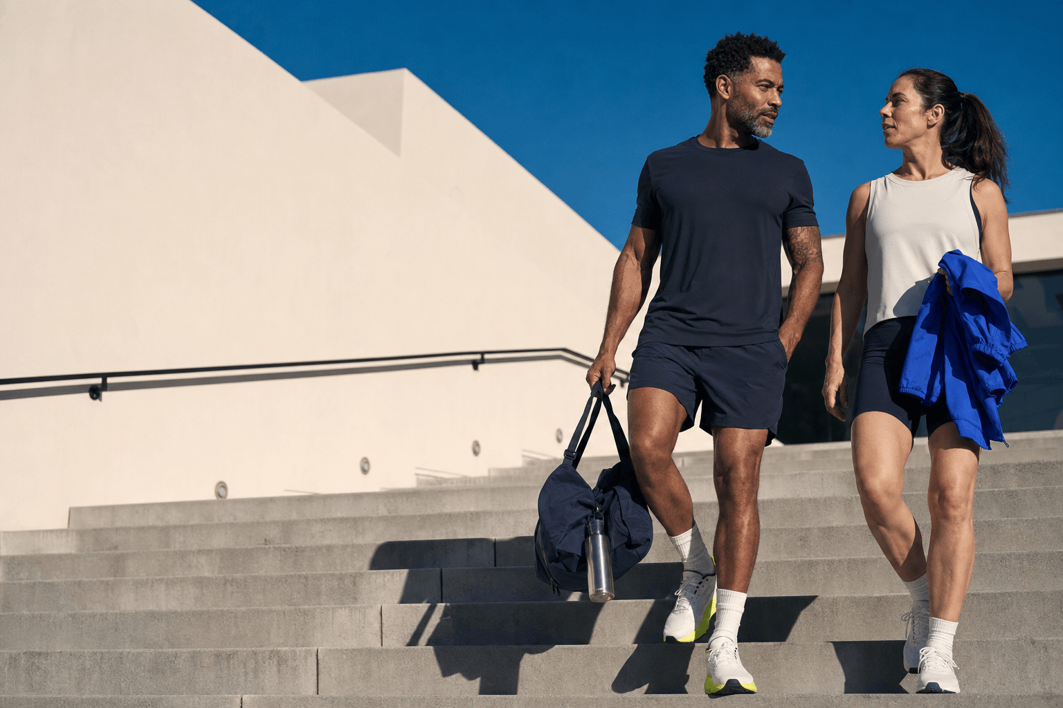 Two adults walking down sunlit steps after a workout.