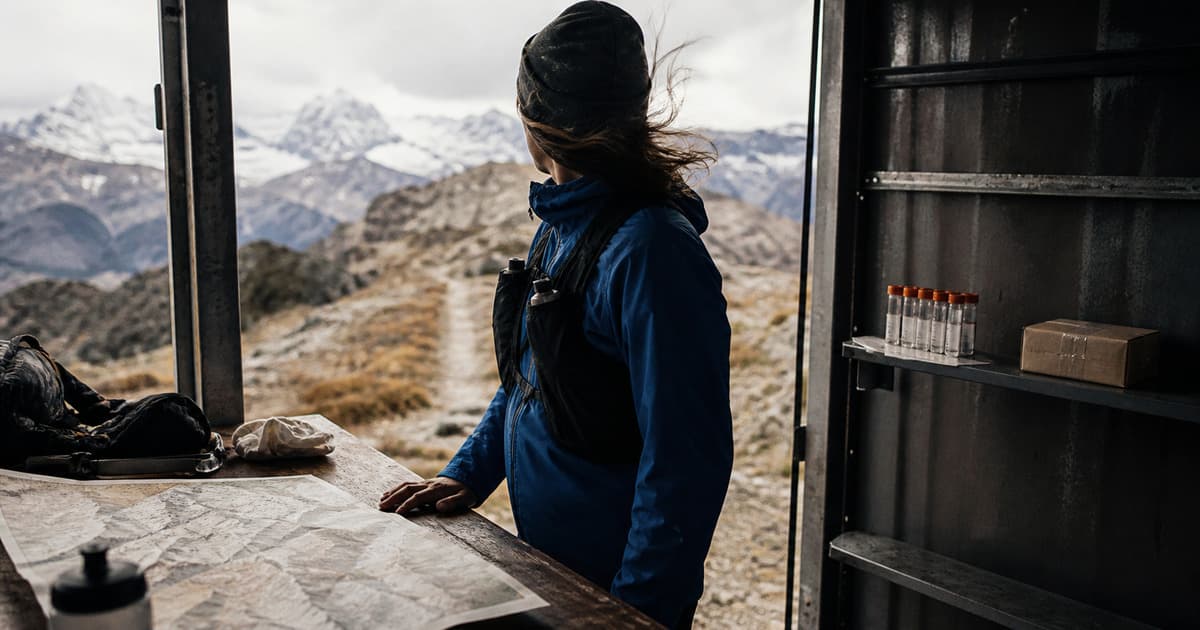 Mountain athlete studying a field map beside unlabeled sample tubes and a treatment parcel