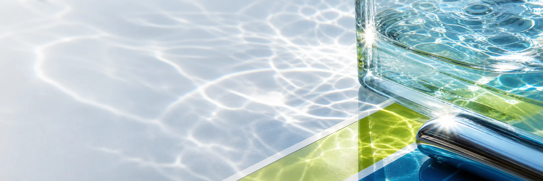Sunlit water caustics across a pale surface with a glass and a lime stripe.