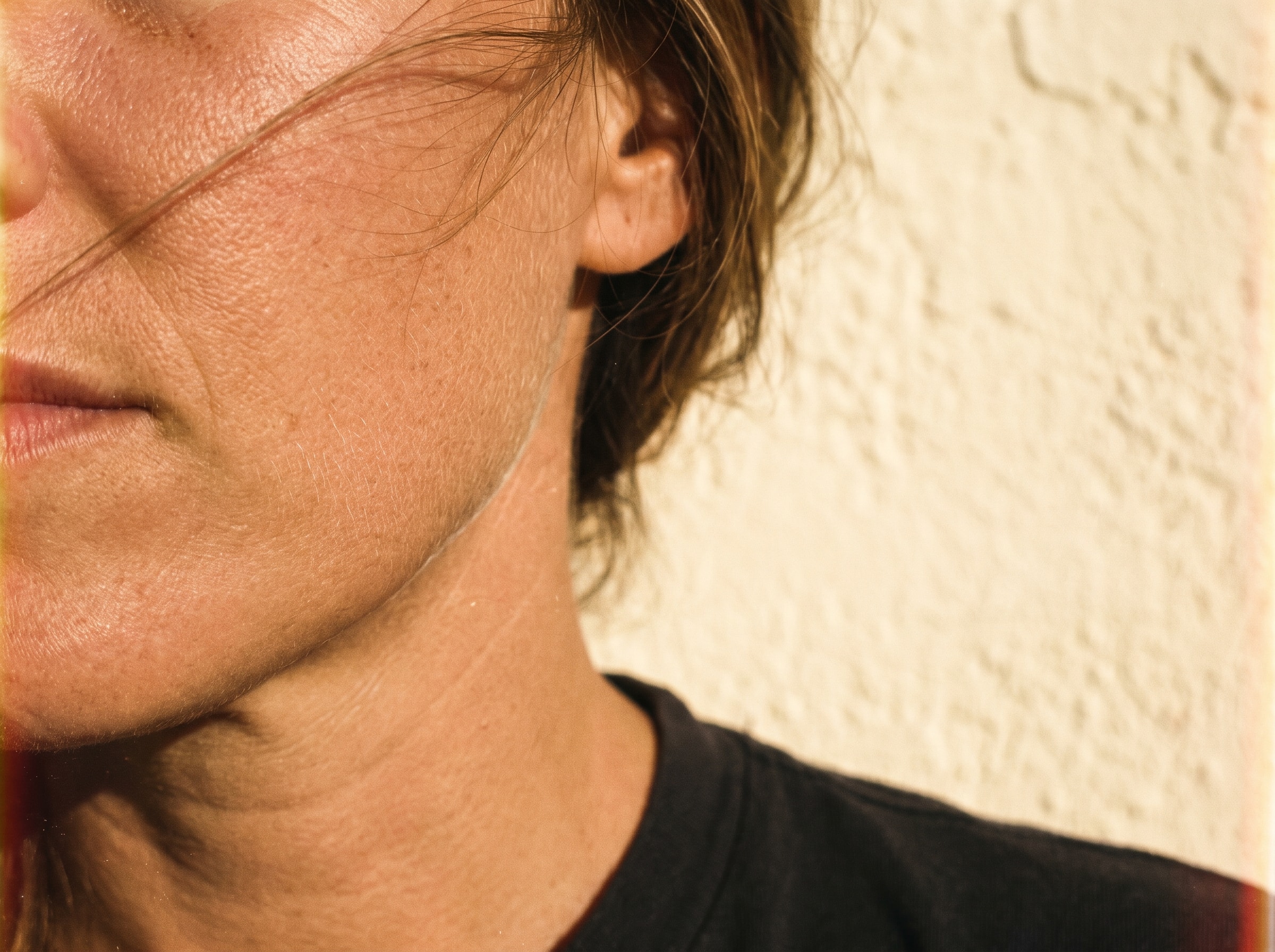 A close crop of a jaw and neck in raking low sun, showing real skin texture.
