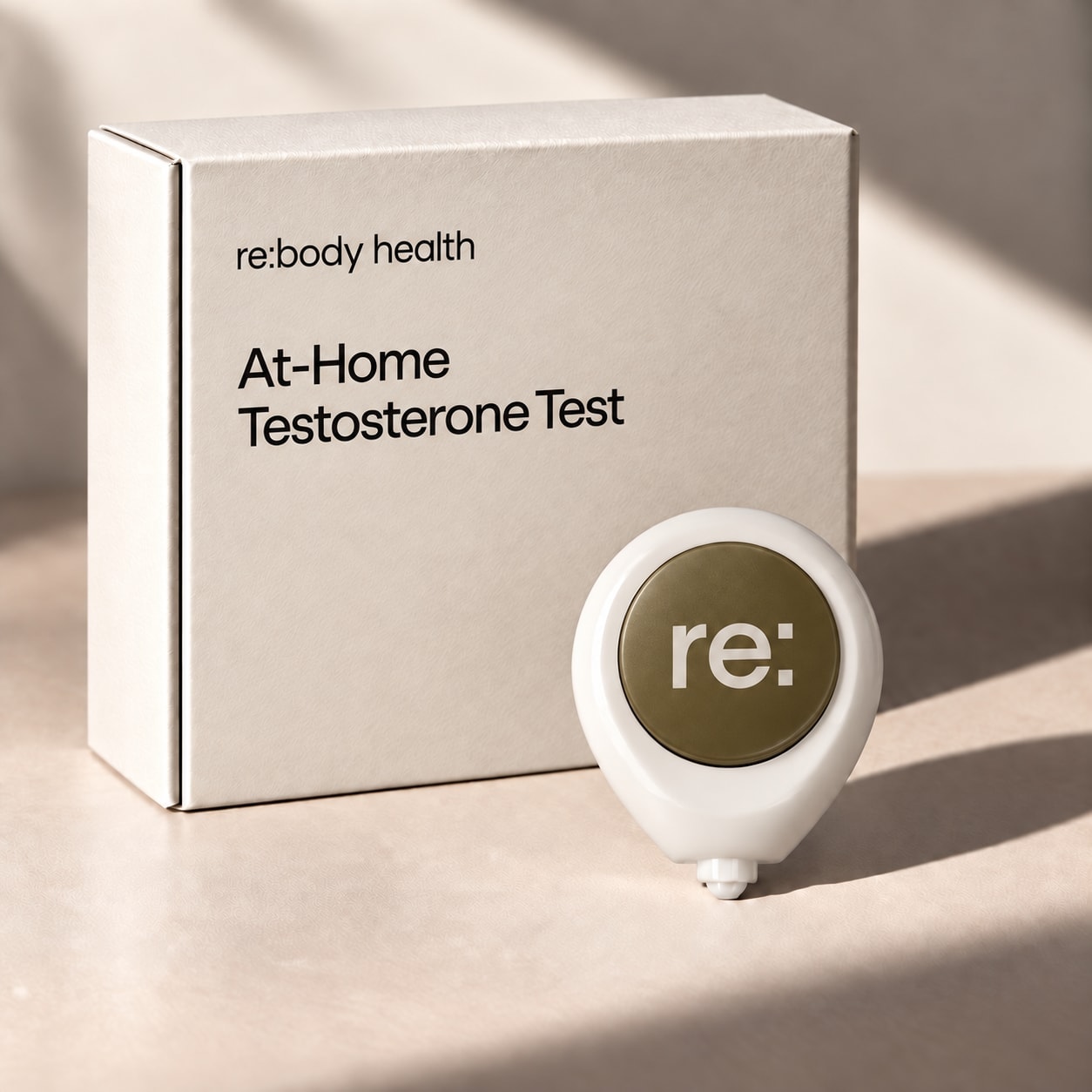 Rebody at-home testosterone test box beside the push-button blood collection device.