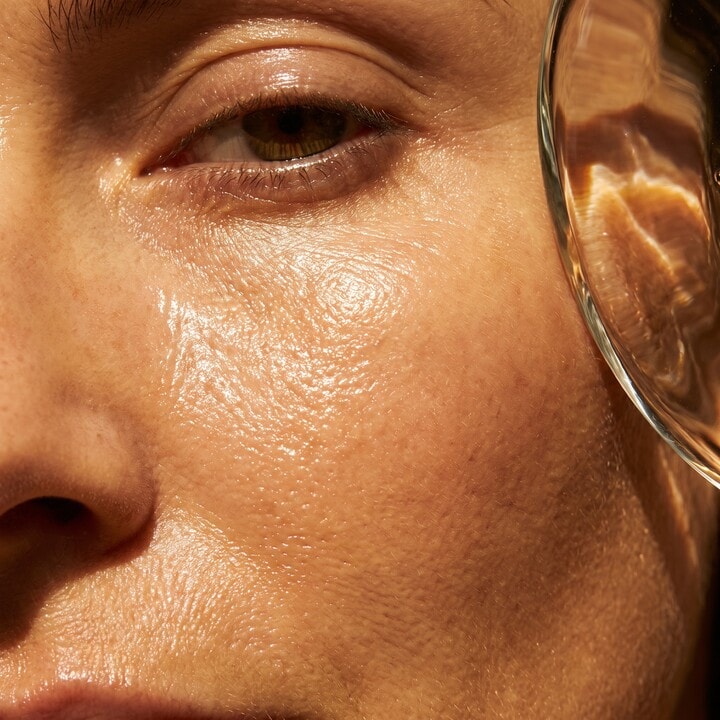 Close luminous skin crop with refracted warm light and clarity.