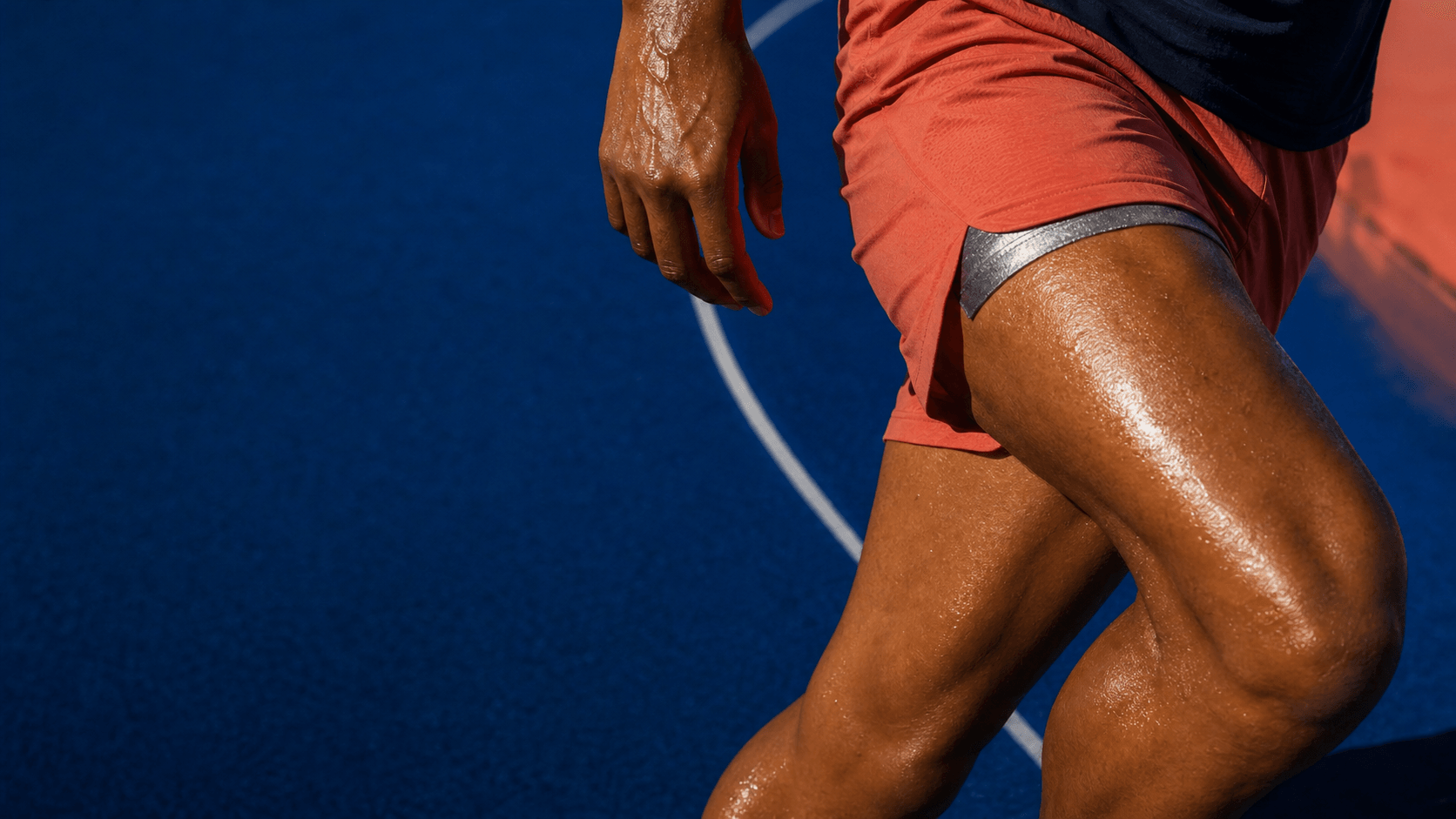 Two adults recovering after a track workout, seen through rain-speckled cobalt glass.