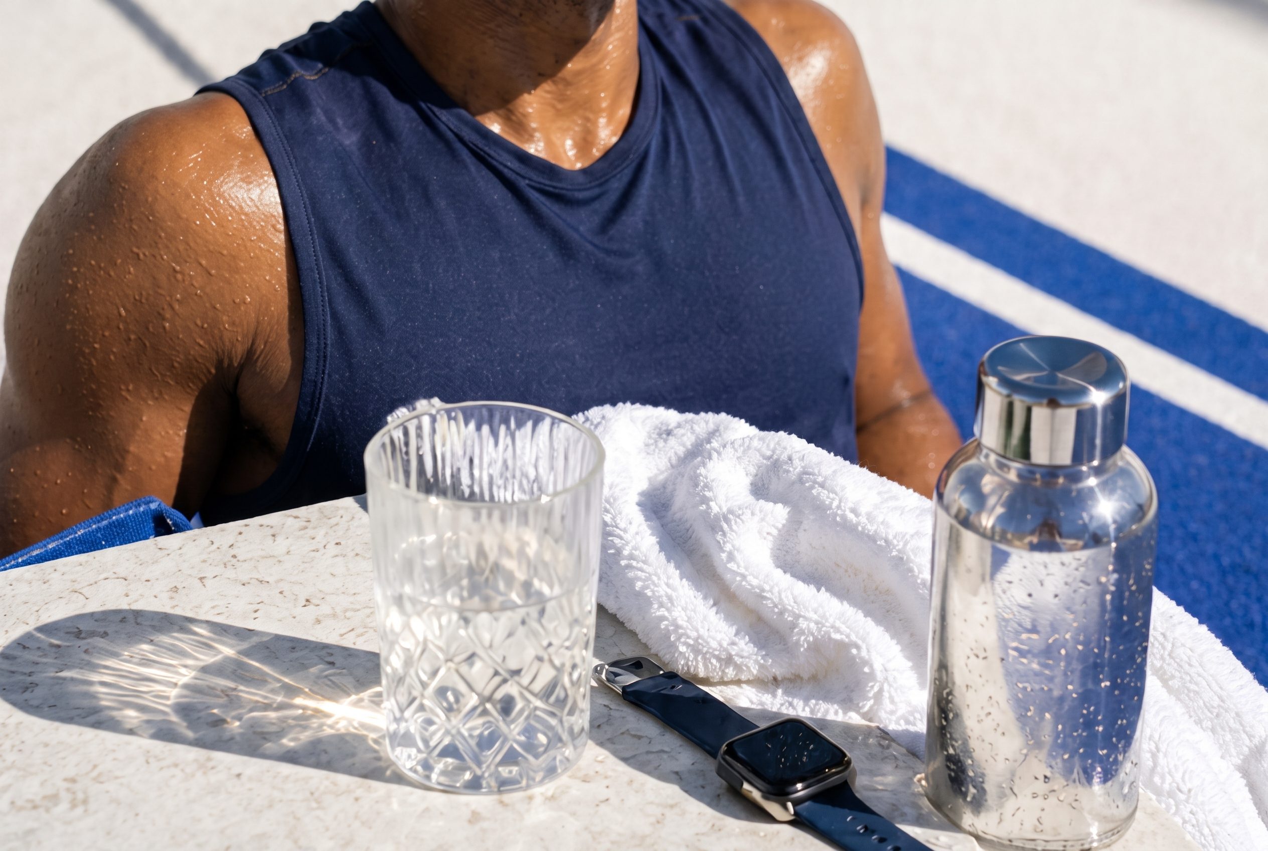 Sunlit recovery scene with activewear, towel fibers, water bottle, watch, glass caustics, and cobalt track.
