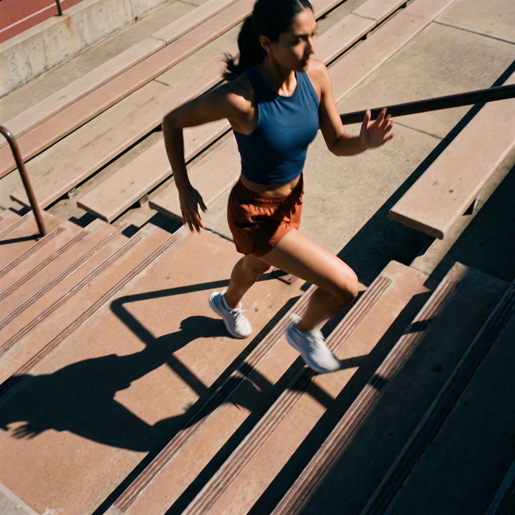 Runner climbing stadium steps in late afternoon light.