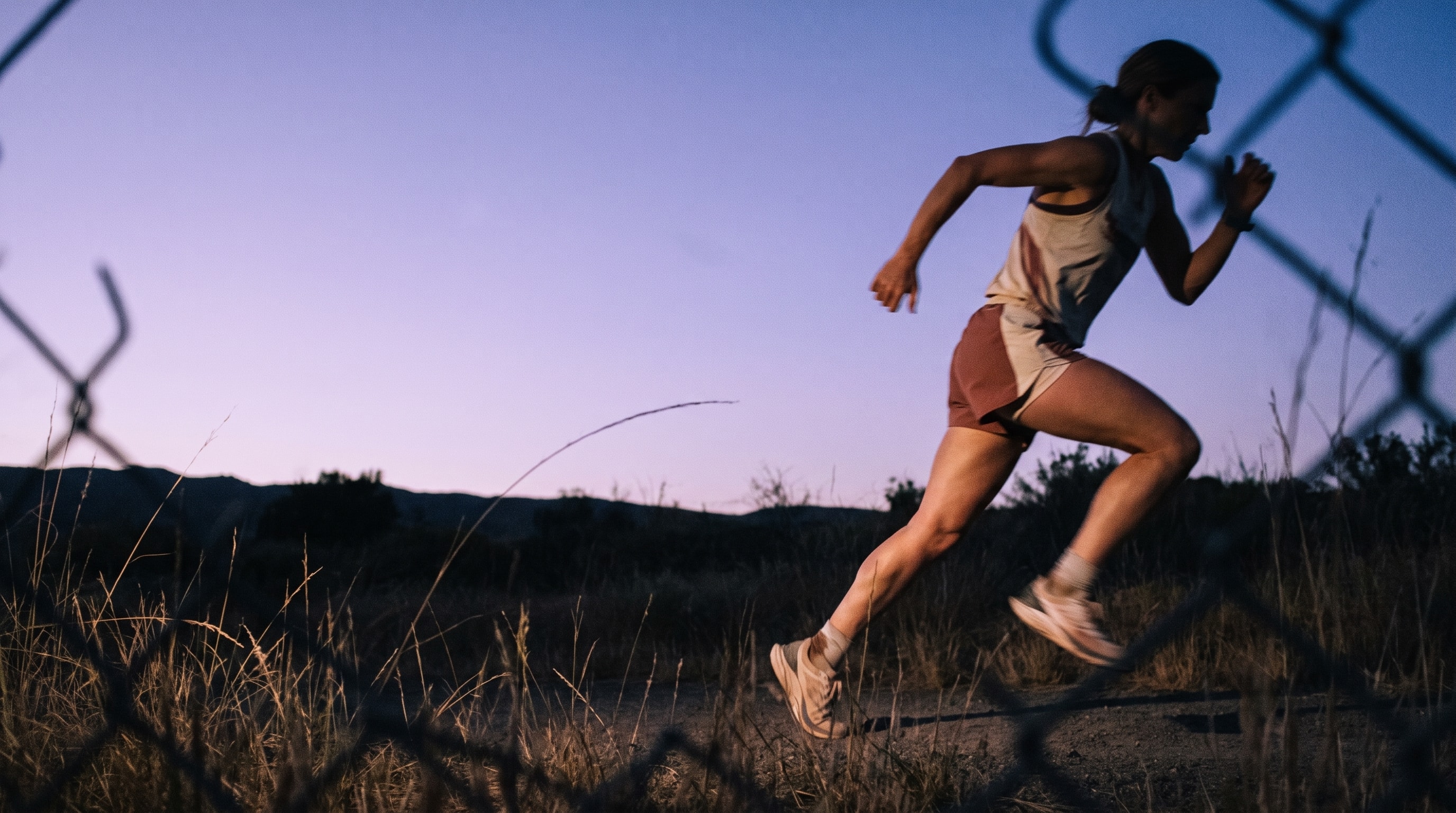 Runner crossing a coastal trail at dusk.
