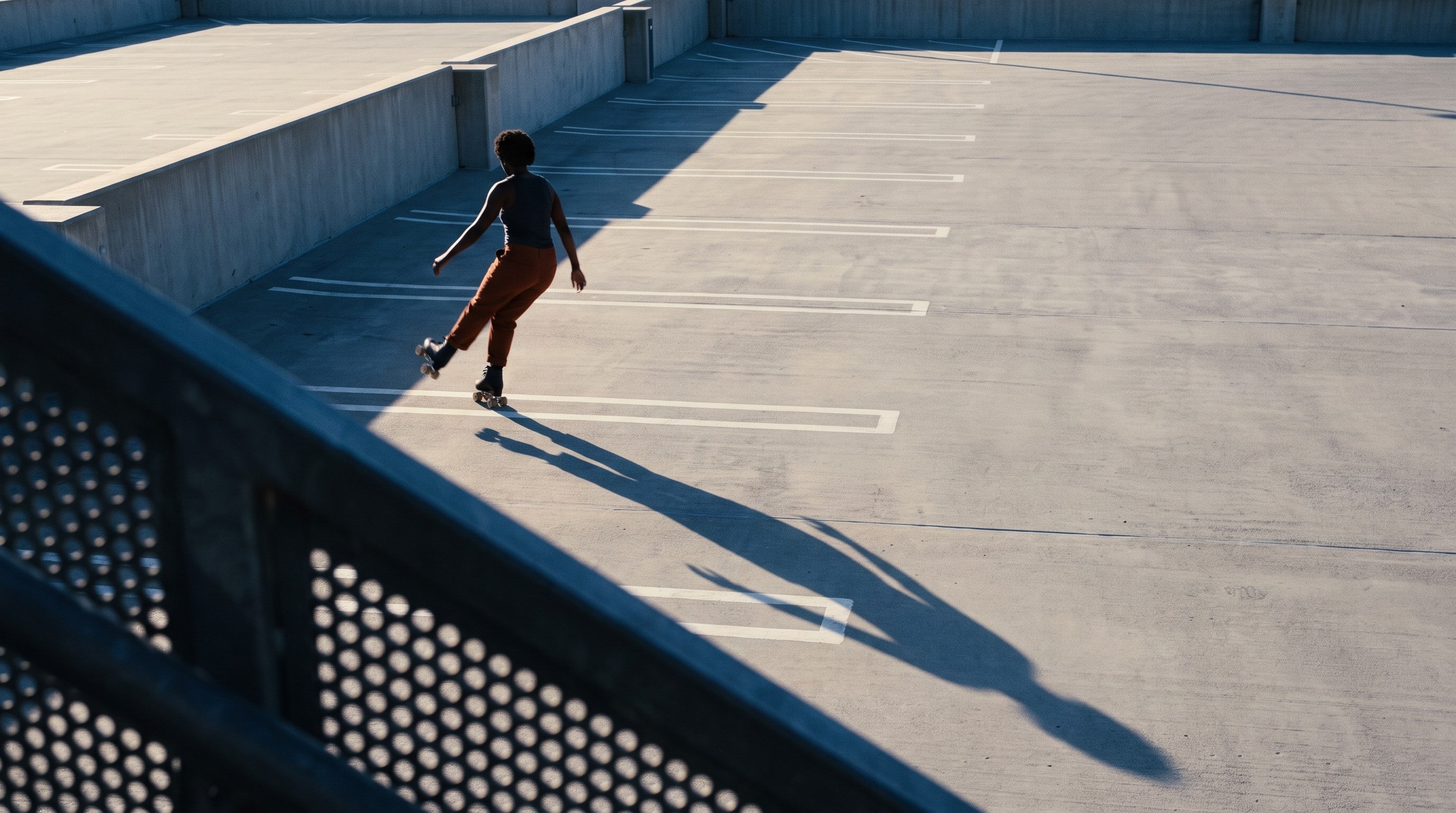 Skater rolling across an empty rooftop parking deck in low sun.