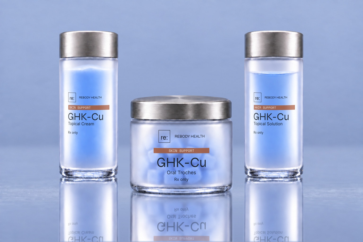 Three frosted Rebody containers for GHK-Cu cream, scalp solution, and oral troches on a glossy slate-blue surface.